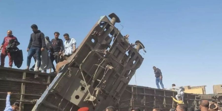Menschen versammeln sich nach dem Zusammenstoss der Züge an den beschädigten Waggons. Foto: Mahmoud Maqboul/dpa