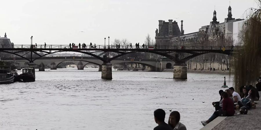 Menschen am Ufer der Seine in Paris. Foto: Lewis Joly/AP/dpa