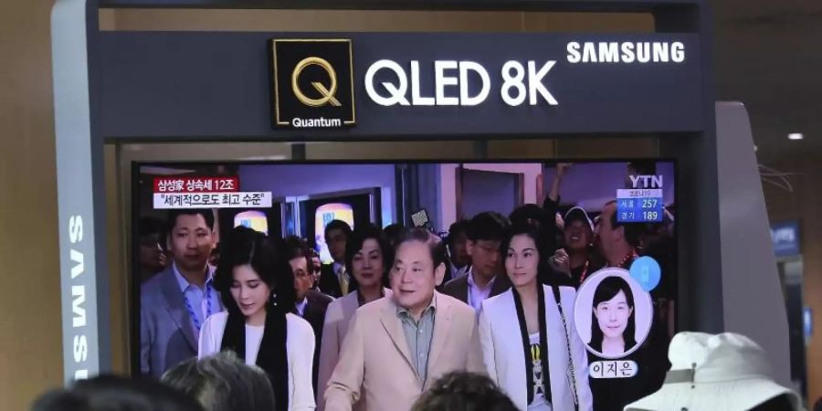 Menschen verfolgen in einer Bahnstation in Seoul eine Nachrichtensendung an einem TV-Gerät. Das Archivbild zeigt Lee Kun-Hee (M) und seine Töchter. Foto: Ahn Young-Joon/AP/dpa