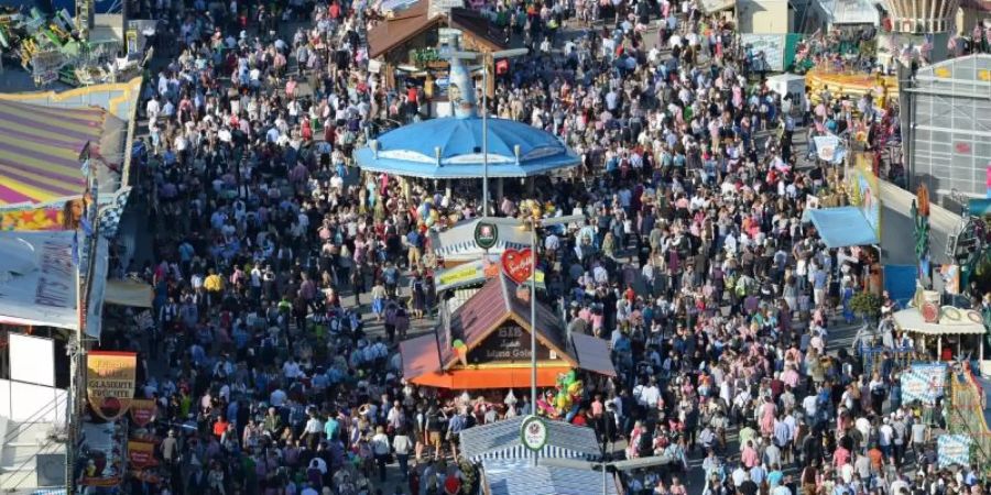 Zahlreiche Menschen gehen bei Sonnenschein über das Oktoberfest-Gelände in München. In der Pandemie scheint ein solches Massen-Fest kaum denkbar. Foto: picture alliance/dpa/Archivbild