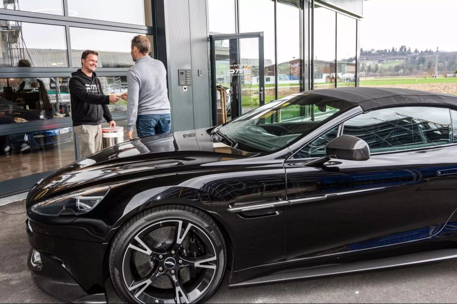 Ein Kunde übergibt die Schlüssel seines Aston Martin an Dominic Beck.