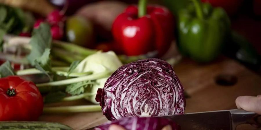 Eine Frau schneidet auf einem Schneidbrett mit einem Küchenmesser einen Radicchio. Foto: Fabian Sommer/dpa