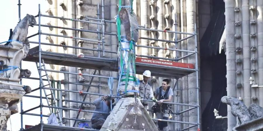 Arbeiter bereiten eine Statue auf einem Dach von Notre-Dame auf die Demontage durch einen Kran vor. Foto: Michel Euler/AP POOL