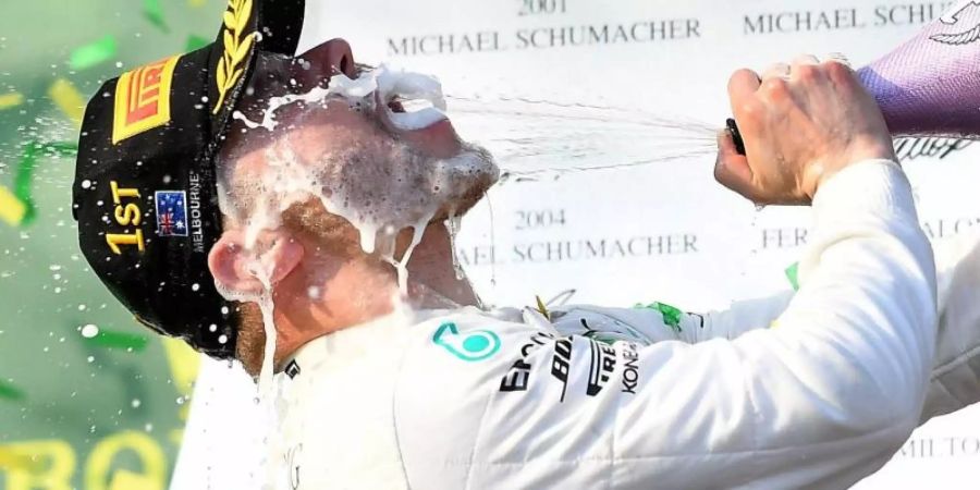 Mercedes-Pilot Valterri Bottas aus Finnland feiert seinen Sieg auf dem Podium mit Champagner. Foto: Julian Smith/AAP