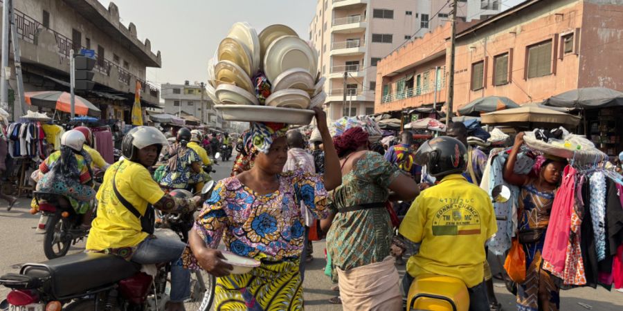 ARCHIV - Eine Tellerverkäuferin macht sich auf den Weg zum Markt in Cotonou. Foto: Sunday Alamba/AP/dpa
