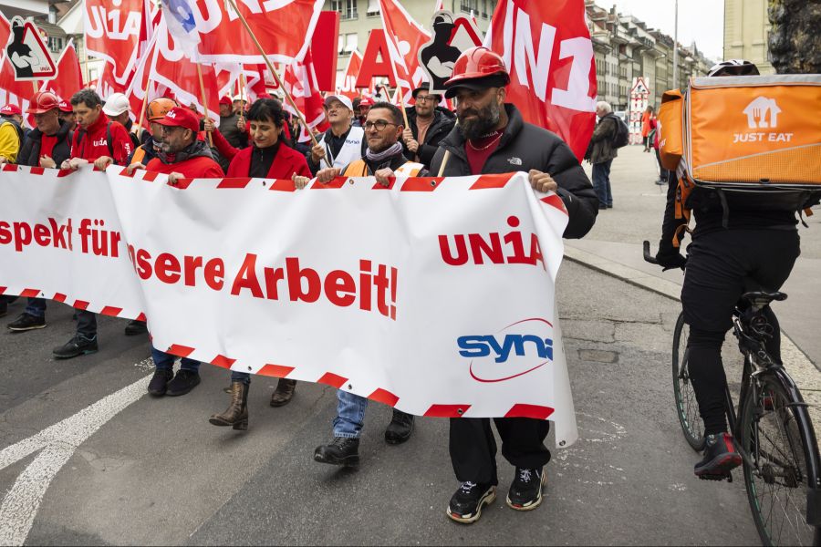 Die Gewerkschaften fordern mehr Schutz für Kuriere. Abgebildet: Ein Just-Eat-Fahrer fährt an einer Unia-Demo für Bauarbeiter vorbei.