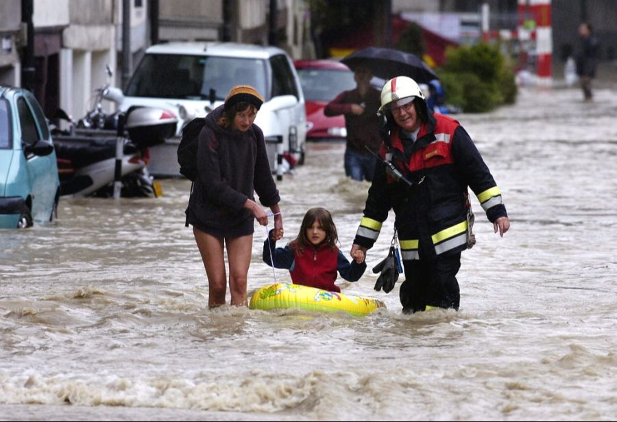 Mit Unterstützung durch einen Feuerwehrmann zieht eine Frau ihre Tochter auf einem Gummiboot durch die überfluteten Strassen im Berner Mattequartier, am 22. August 2005.