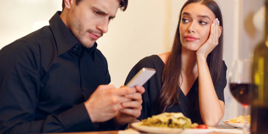 frau und mann sitzen an tisch, sie schaut herablassend