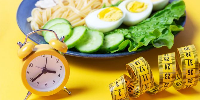 Teller mit Essen, Massband und Uhr.