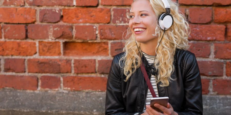 Junge Frau hört Musik über ihr Smartphone
