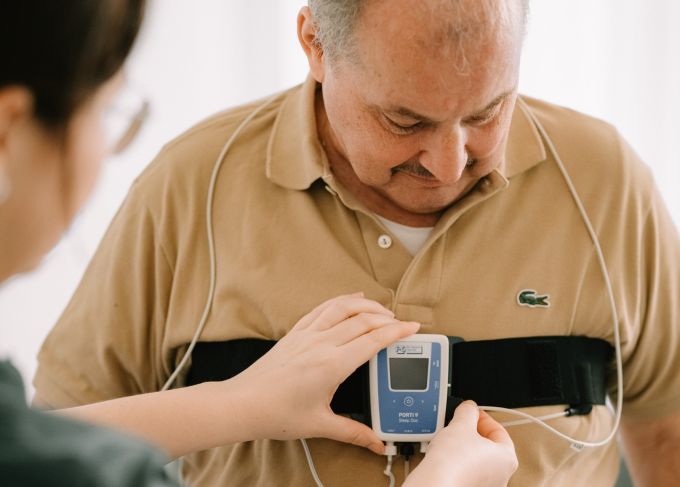 Eine Fachperson am KSA legt einem Patienten ein mobiles Gerät zur Messung der Schlafaktivitäten an. Gesundheit Aargau