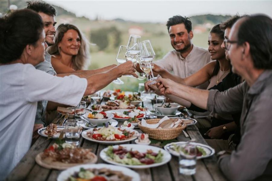 «Prost!»: Freunde sitzen um einen reich gedeckten Tisch mit südsteirischen Köstlichkeiten.