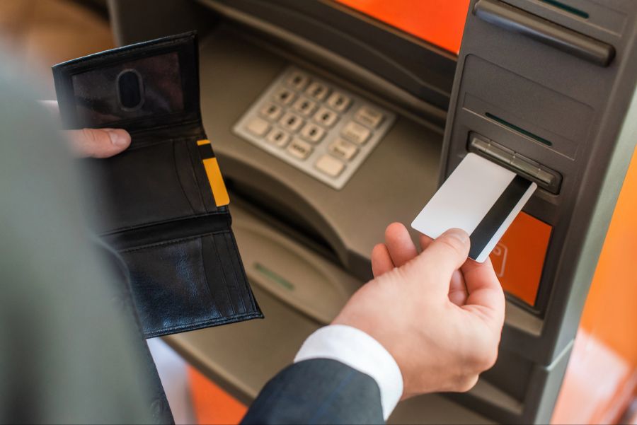 Person schiebt Bankkarte in einen Geldautomaten