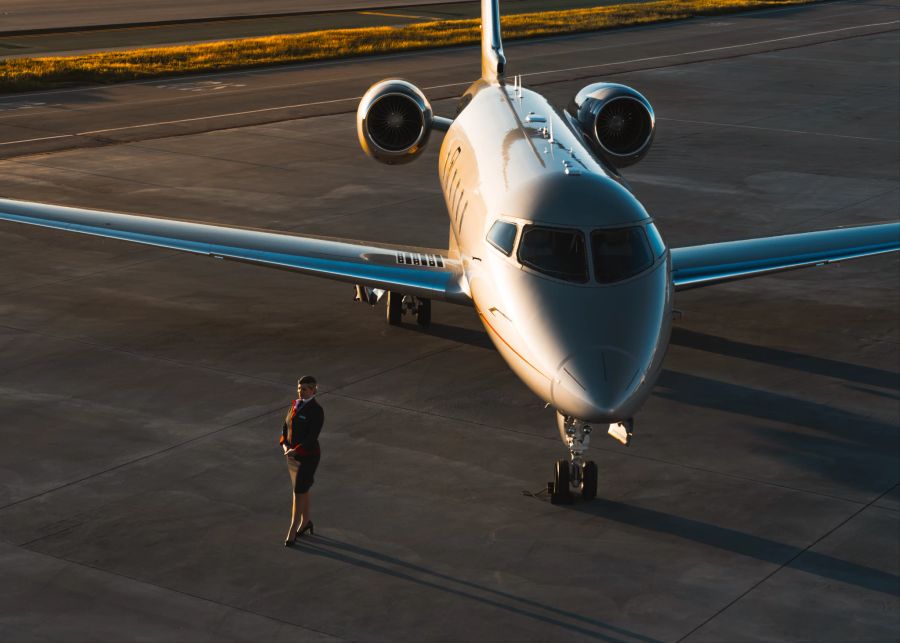 Stewartdess vor einem Privatjet auf der Landebahn.