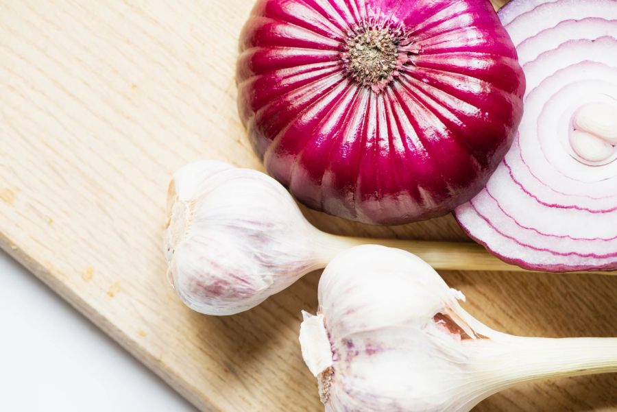 Frischer Knoblauch und Zwiebeln auf Holzbrett