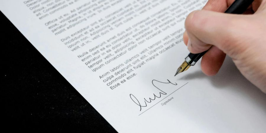 Eine Person unterzeichnet einen Brief.
