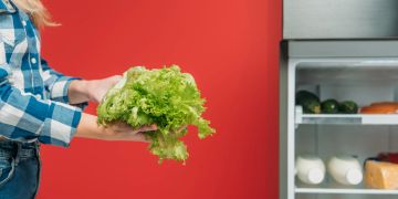 Frau mit Salat vor Kühlschrank