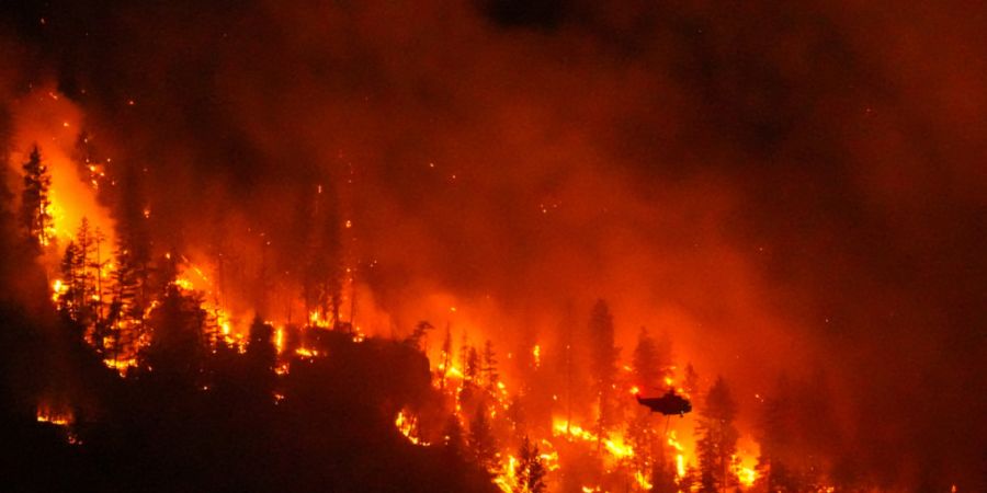 ARCHIV - Ein Hubschrauber wirft Wasser auf den Waldbrand am Quilpituk Creek auf der Westseite des Okanagan-Sees in British Columbia ab. Foto: Darryl Dyck/The Canadian Press via AP/dpa