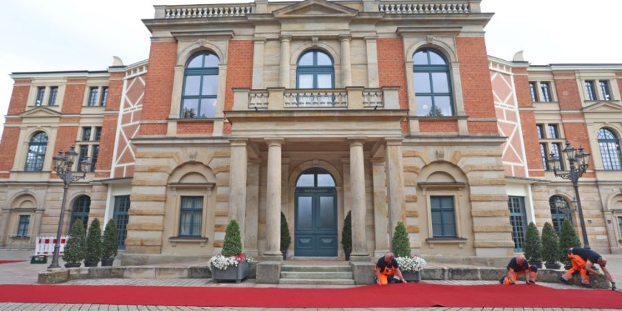 ARCHIV - Der rote Teppich wird für die Eröffnung der Bayreuther Richard-Wagner-Festspiele vor dem Festspielhaus auf dem Grünen Hügel befestigt. Foto: Karl-Josef Hildenbrand/dpa