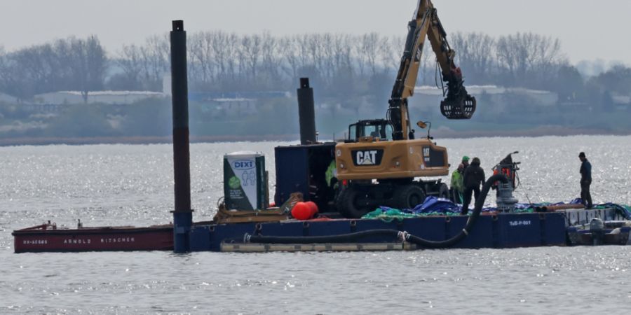 Ein Arbeitsponton mit einem speziellen Bagger und kleinere Begleitboote sind in der Nähe des gestrandeten Buckelwals vor der Insel Poel im Einsatz. Foto: Bernd Wüstneck/dpa