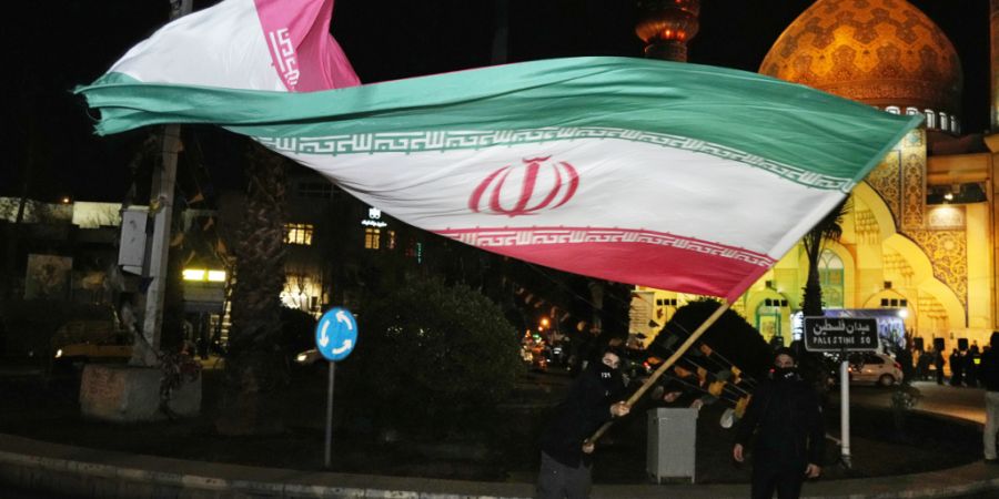 ARCHIV - Ein Demonstrant schwenkt eine iranische Flagge bei einer Feier anlässlich der Ankündigung einer Waffenruhe zwischen der Hamas und Israel auf dem Felestin (Palästina) Platz i...