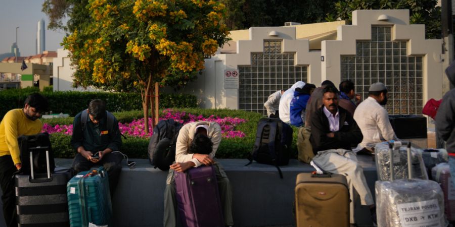 Passagiere, die durch die Schließung des internationalen Flughafens von Dubai gestrandet sind, warten auf dem Flughafenparkplatz in Dubai. Foto: Altaf Qadri/AP/dpa