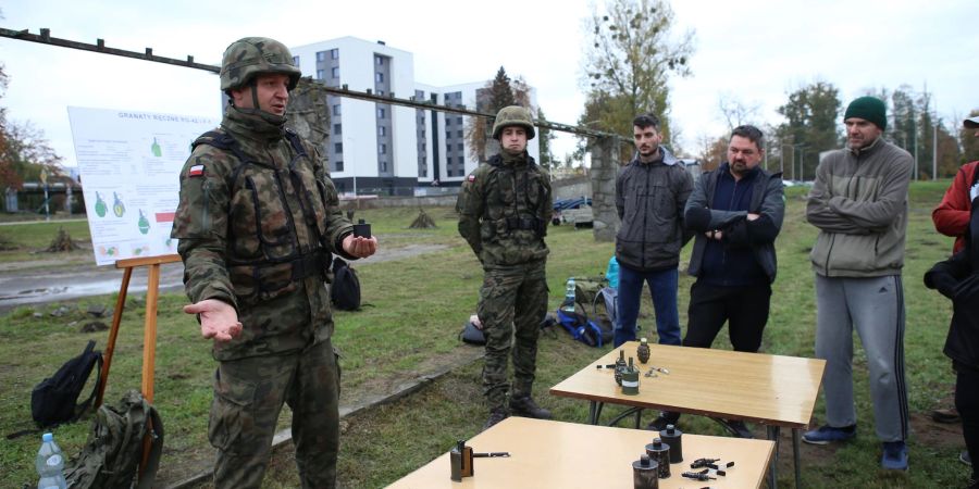 Oberfeldwebel Mariusz Starosz (l) erklärt auf einem Übungsplatz der polnischen Armee Bürgern den richtigen Umgang mit einer Handgranate.