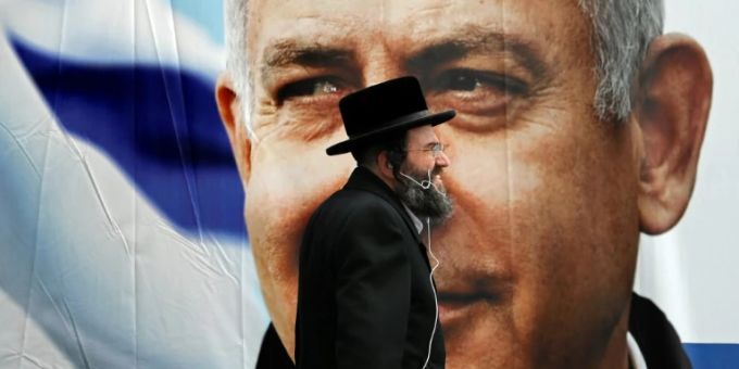 Israels höchstes Gericht entschied, dass auch ultraorthodoxe Männer zum Wehrdienst in der Armee verpflichtet werden müssen. (Symbolbild) Ultraorthodoxer Mann vor Wahlplakat mit Benjamin Netanjahu
