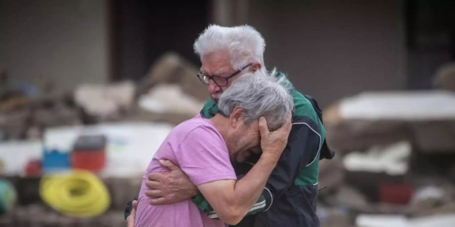 Weinend liegen sich die Brüder Bernd (l) und Gerd Gasper vor ihrem von der Flut zerstörten Elternhaus in Altenahr in den Armen. Foto: Boris Roessler/dpa