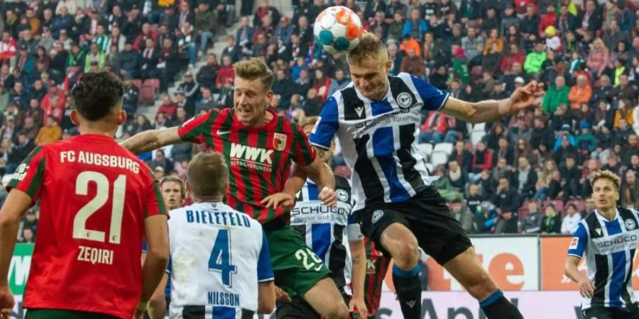 Augsburgs Andre Hahn (hinten, l) und Bielefelds Amos Pieper im Kopfballduell. Foto: Stefan Puchner/dpa
