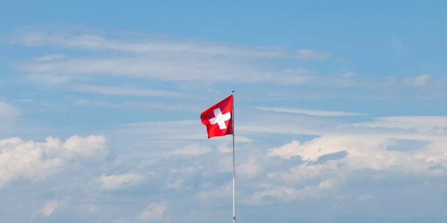 Eine Schweizerfahne vor Wolkenhimmel.