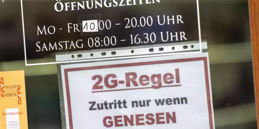 Ein Schild zur «2G-Regel» hängt an der Eingangstür eines Münchner Friseurladens. Foto: Peter Kneffel/dpa