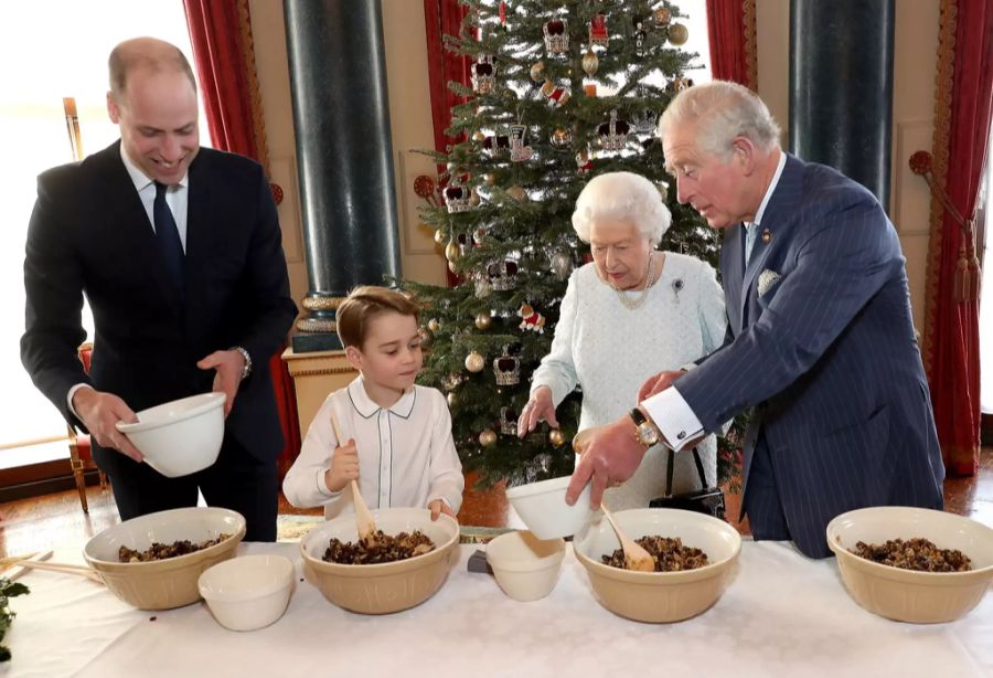 Prinz William, Prinz George, Queen Elizabeth II. und Prinz Charles am Backen, im Hintergrund ein geschmückter Baum zur Weihnachtszeit 2019.