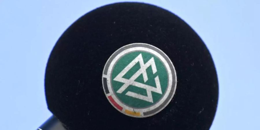 Das Logo des Deutschen Fussball-Bundes (DFB) auf einem Mikrofon. Foto: Swen Pförtner/dpa