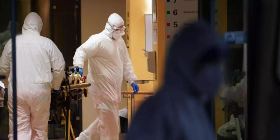 Sanitäter schieben in einem Seniorendomizil im Stadtteil Lichtenberg eine Tragbahre. Foto: Jörg Carstensen/dpa