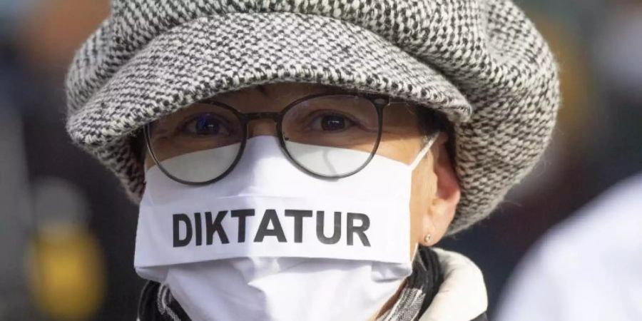 "Diktatur" steht auf der Nase-Mund-Bedeckung" einer Teilnehmerin an einer "Querdenken"-Demonstration in Frankfurt am Main. Foto: Boris Roessler/dpa