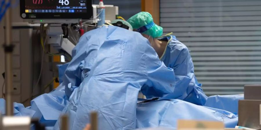 Medizinisches Personal legt auf einer Intensivstation einem Covid-19-Patienten einen Zugang für die künstliche Beatmung. Foto: Sebastian Gollnow/dpa