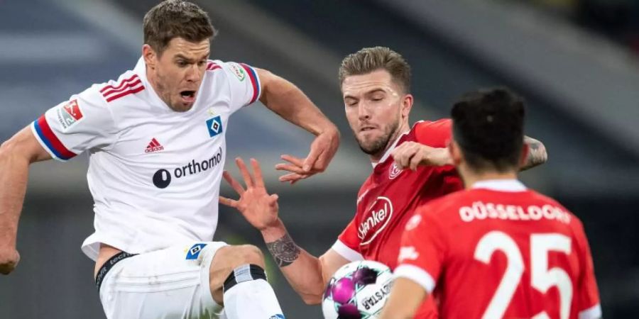 Düsseldorfs André Hoffmann (M) und HSV-Torjäger Simon Terodde teilten sich im Spitzenspiel die Punkte. Foto: Marius Becker/dpa