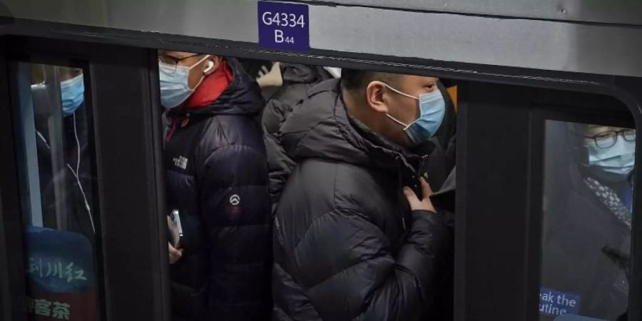 Pendler in Peking drängen sich während der Hauptverkehrszeit in eine U-Bahn. Foto: Andy Wong/AP/dpa
