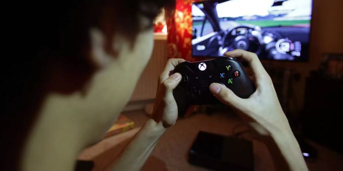 Ein Teenager, der einen Controller hält, um ein Videospiel zu spielen. Wahlfach Swisscom