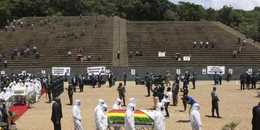 Menschen in Schutzkleidung tragen den Sarg der an Corona verstorbenen Ministerin Dr. Ellen Gwaradzimba. Seit Beginn der Pandemie sind in Simbabwe insgesamt vier Minister an Covid-19-Komplikationen gestorben. Foto: Tsvangirayi Mukwazhi/AP/dpa