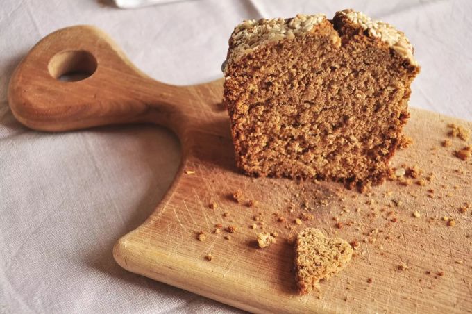 Ein angeschnittenes Vollkornbrot liegt auf einem Holzbrett. Vollkorn