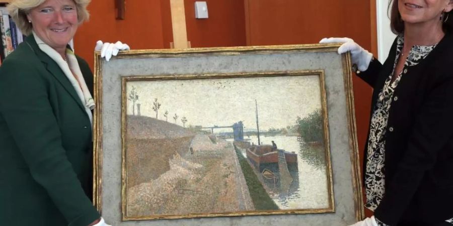 Monika Grütters übergibt das Gemälde «Quai de Clichy» von Paul Signac an die Vertreterin der Erben, Agnès Sevestre-Barbé. Foto: Wolfgang Kumm