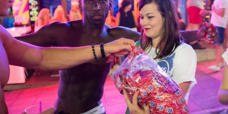 Eine Frau verteilt auf Mallorca Kondome an Touristen.