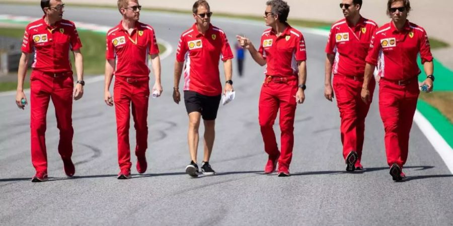 Sebastian Vettel (M) geht mit seinem Team die Rennstrecke in Spielberg ab. Foto: Georg Hochmuth/APA/APA