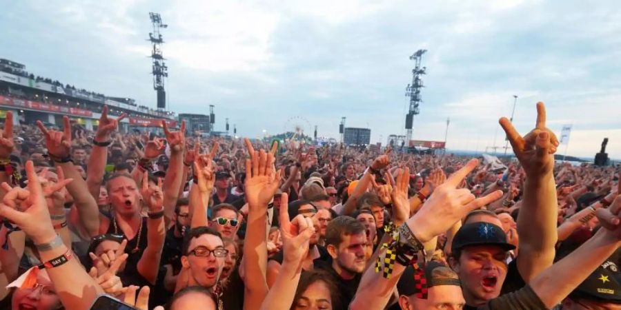 Rockfans jubeln vor der Hauptbühne des Open-Air-Festivals «Rock am Ring». Foto: Thomas Frey/dpa