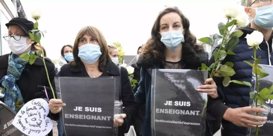 Mit Schildern mit Aufschriften wie «Ich bin Lehrer - Ich verteidige die Meinungsfreiheit» kommen Menschen in Conflans-Sainte-Honorine zum Gedenken zusammen. Foto: Bertrand Guay/AFP/dpa