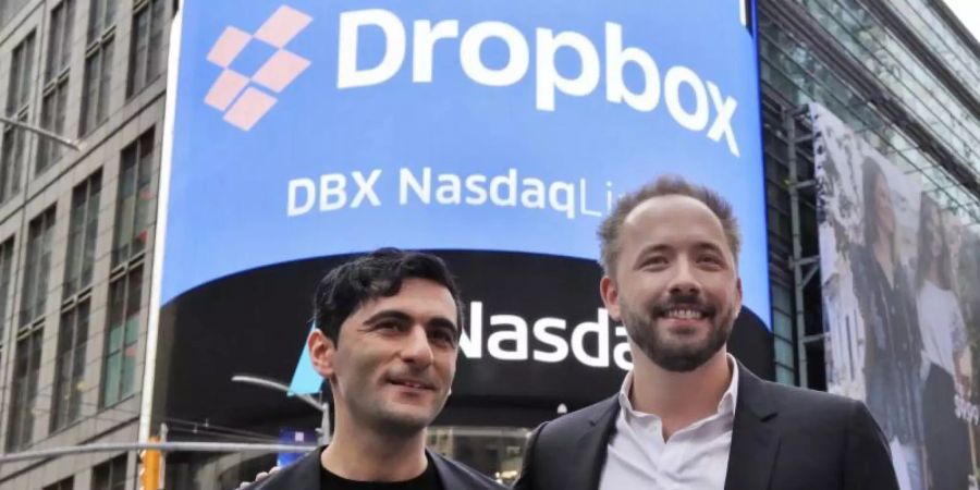 Arash Ferdowsi (l) und Drew Houston, Gründer des Online-Speicherdienstes Dropbox, stehen vor einem Plakat zum Börsengang ihres Unternehmens. Foto: Richard Drew/AP/dpa