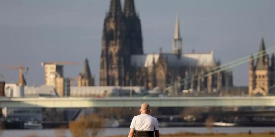 T-Shirt im Dezember: Ein Mann geht bei milden Temperaturen am Kölner Rheinufer in der Nachmittagssonne spazieren. Foto: Oliver Berg/dpa