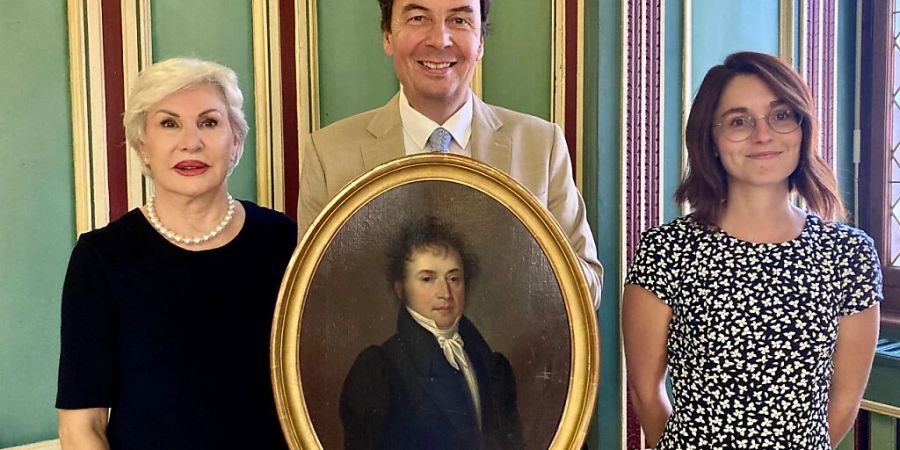 Der Sittener Stadtpräsident Philippe Varone (Mitte) mit dem wieder aufgefundenen Gemälde, flankiert von der Besitzerin Emmanuelle de Kalbermatten (links) und der Stadtarchivarin Coline Remy (r.).